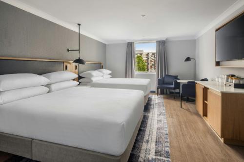 a hotel room with two beds and a desk at Edinburgh Marriott Hotel Holyrood in Edinburgh