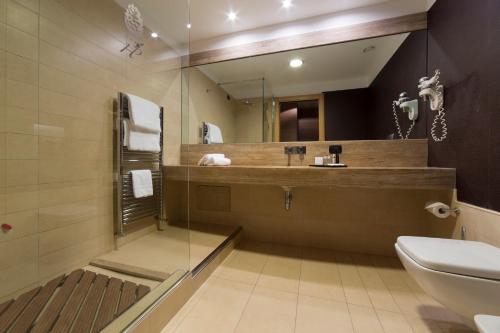 ルーヴォ・ディ・プーリアにあるHotel Pineta Wellness & Spaのバスルーム(洗面台、トイレ、鏡付)