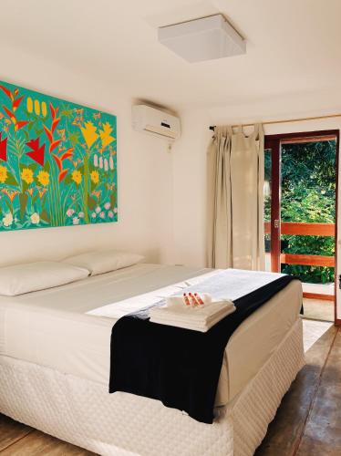 a bedroom with a bed with a painting on the wall at Pousada Casa de Inaê in Itacaré