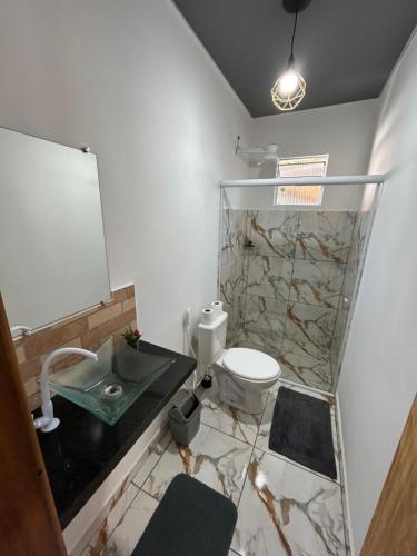 a bathroom with a toilet and a sink and a mirror at Cataventooo hospedagens in Miguel Pereira