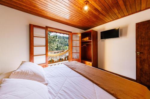 a bedroom with a large bed and a window at Pousada Sonho Verde in Monte Verde