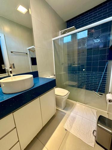 a bathroom with a sink and a toilet and a glass shower at Pousada Alphaville in Palmas