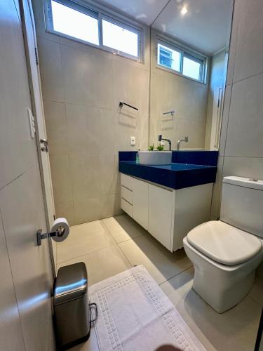 a bathroom with a white toilet and a blue sink at Pousada Alphaville in Palmas