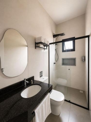 a bathroom with a sink and a toilet and a mirror at HOTEL SB Butia in Butiá