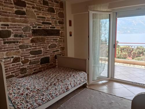 a bedroom with a brick wall and a bed next to a window at Ilios in Pogoniá