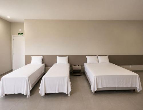 two beds with white sheets in a room at HOTEL SB Butia in Butiá