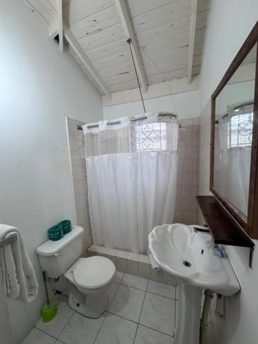 a white bathroom with a toilet and a sink at 1Fusion2 in Negril