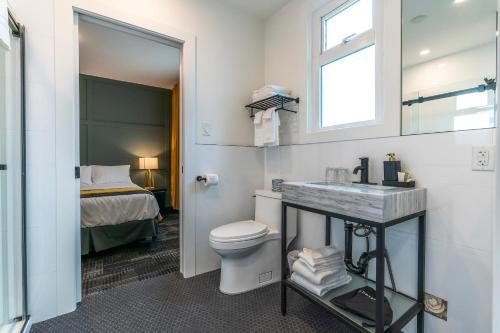 a bathroom with a toilet and a sink and a bed at Steveston Cafe & Hotel in Richmond