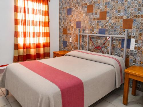 a bedroom with a bed and a wall with tiles at Hotel Posada el Cid in Oaxaca City