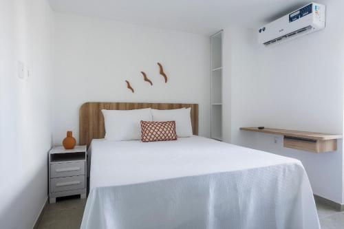 a bedroom with a white bed with a wooden headboard at Apartamentos mobiliados em Caruaru in Caruaru