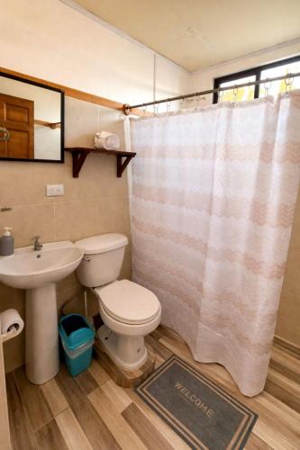 a bathroom with a toilet and a sink and a shower curtain at Brisas Griegas in Quepos