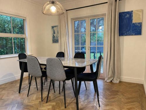 a dining room with a table and chairs and windows at Wood Street Haven in Greytown