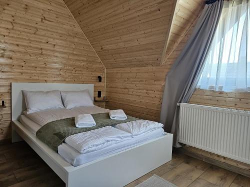 a bed in a room with a wooden wall at Tatrzańska Osada 2 - Domki przy stoku narciarskim w Białce Tatrzańskiej in Białka Tatrzańska