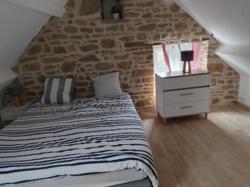 a bedroom with a bed and a stone wall at L' Eminence in Clécy