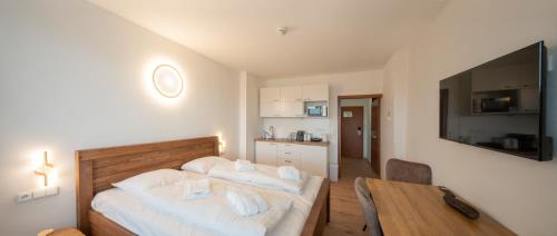 a bedroom with a bed and a table and a kitchen at Lipno - apartmán C404 in Frymburk