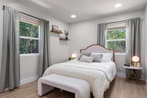 a white bedroom with a large bed and two windows at Charming house in Midtown District in Reno