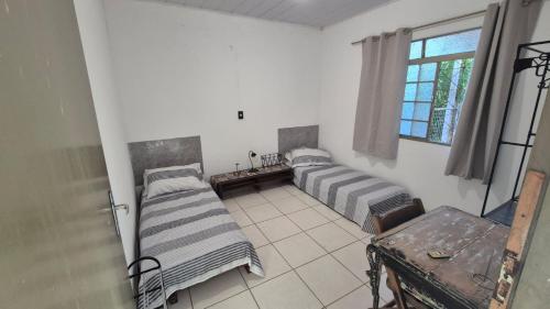 two beds in a room with a window at Casa Pitanga Quarto in Barra do Garças