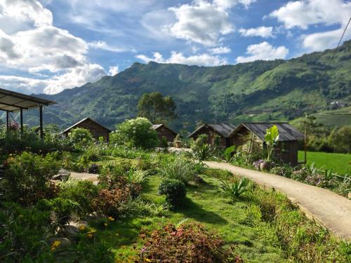 a path through a garden with mountains in the background at De Mont Retreat Sapa in Sapa