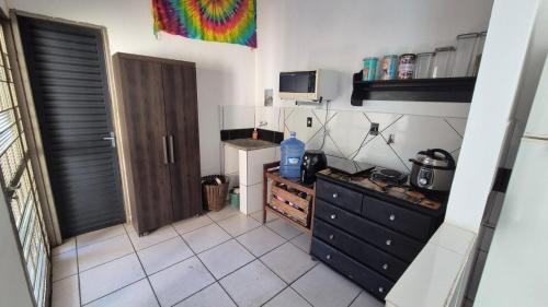 a kitchen with a black dresser and a microwave at Casa Pitanga Quarto in Barra do Garças