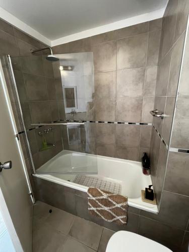 a bathroom with a tub and a shower with a toilet at Urquiza Suite Premium Rental in Buenos Aires