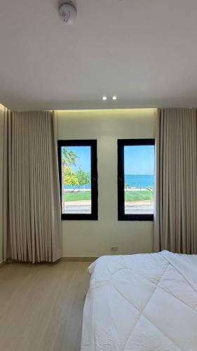 a bedroom with three windows with the ocean in the background at Pearl sea in Al Jubail