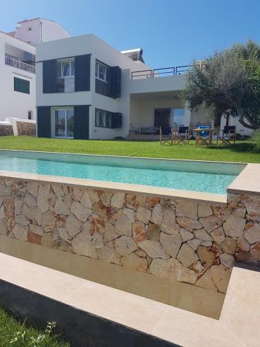 a swimming pool in front of a house at Agua en las Rocas in Sa Caleta