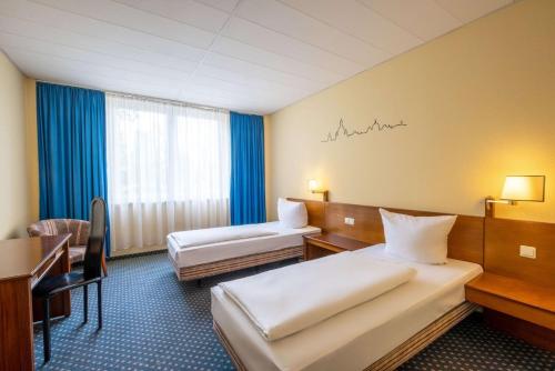 ein Hotelzimmer mit zwei Betten und einem Schreibtisch in der Unterkunft Quick Hotel Dresden 24H Self Check-in in Dresden