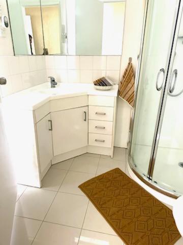 a bathroom with a shower and a sink and a mirror at Private 2-Bedroom Suite in 3-Bedroom House in Auckland