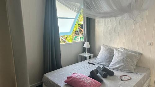 a bedroom with a bed with a window at LE FARE BLEU DUO 2 chambres climatisées avec 1 salle de bain - bord de lagon à Tiputa Rangiroa - vélos gratuits et snorkeling in Rangiroa