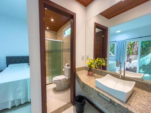 a bathroom with a sink and a bed and a mirror at Pousada Pénareia in Morro de São Paulo