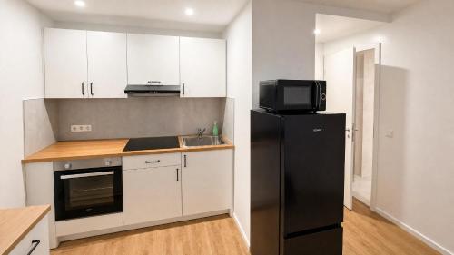 a kitchen with a black refrigerator and a microwave at CityNest Apartment Mülheim in Mülheim an der Ruhr