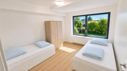 two beds in a room with a large window at CityNest Apartment Mülheim in Mülheim an der Ruhr