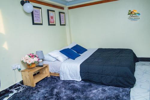 a bedroom with a bed with blue pillows and a table at Shan in Jinja