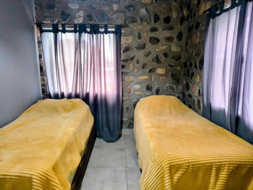 a room with two beds and a window with curtains at Cabañas 2TIERRAS in Chicoana