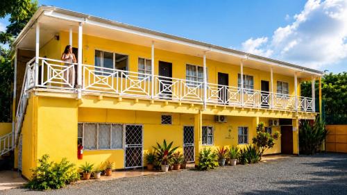 a woman standing on the balcony of a yellow building at Casa Amarilla Caribbean Stay in Puerto Limón