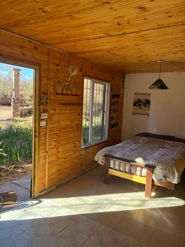 a bedroom in a log cabin with a bed in it at Rancho Por Fin in Barreal