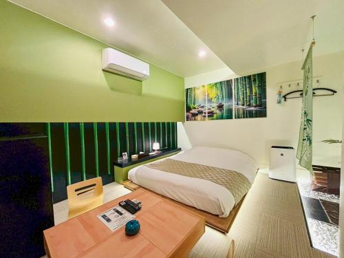 a green bedroom with a bed and a table at HOTEL 壮-soh-shibuya in Tokyo