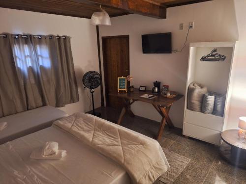 a room with a bed and a desk and a refrigerator at Pousada Pindobas in Venda Nova do Imigrante