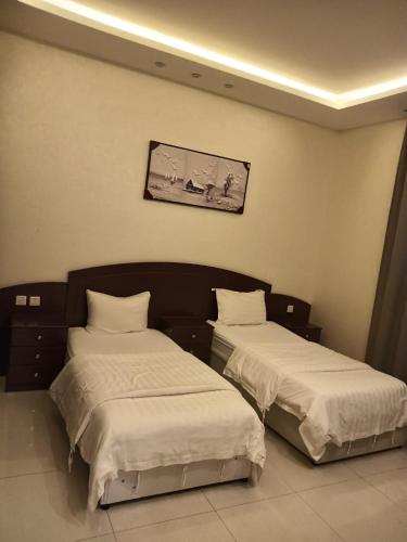 two beds in a room with white sheets at شقق فندقيه in Buraydah