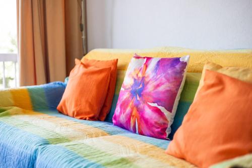 a couch with colorful pillows on it at Malgré Tout 0312 in Koksijde