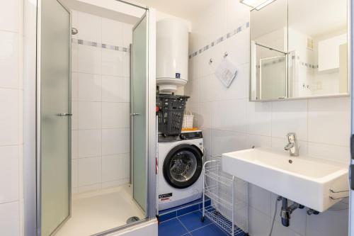 a bathroom with a washing machine and a sink at Malgré Tout 0312 in Koksijde
