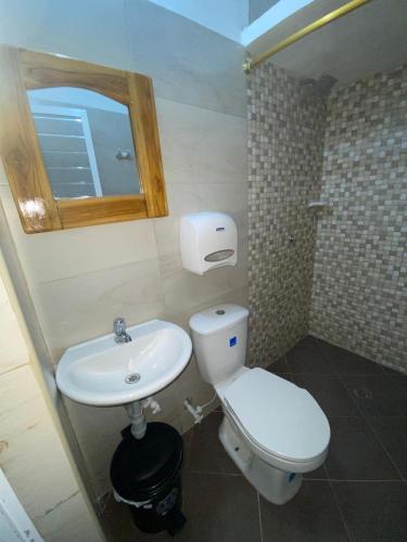 a bathroom with a toilet and a sink and a mirror at Hotel La Cima in Arboletes
