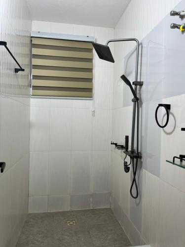 a white bathroom with a shower with a window at Serene Coastal Escapes GH in Prampram
