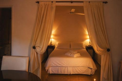 チャスコムスにあるApart Hotel Las Moraditas - a 50 metros de la Lagunaのカーテンとテーブル付きのベッドのある寝室