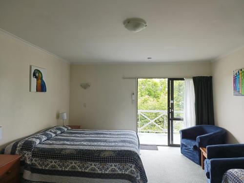 a bedroom with a bed and a chair and a window at Raceway Motel in Christchurch