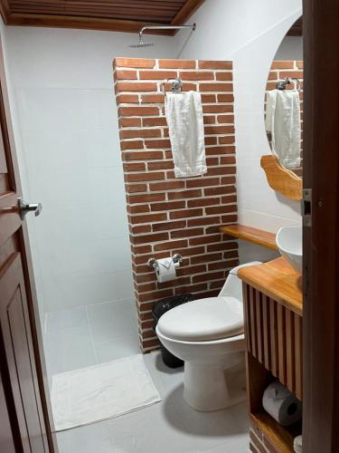 a bathroom with a white toilet and a brick wall at Hotel Termales Espiritu Santo in Nariño