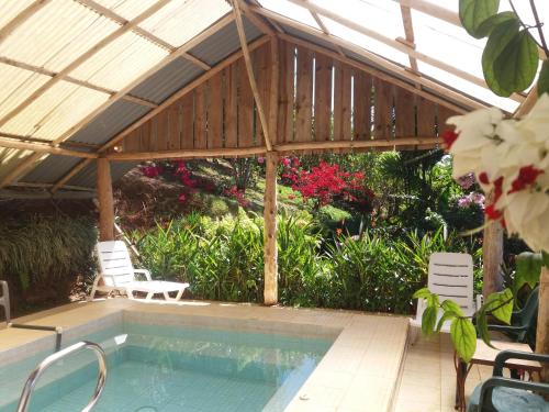 a swimming pool under a wooden pergola with two chairs at La Princesa Hotel in San Isidro