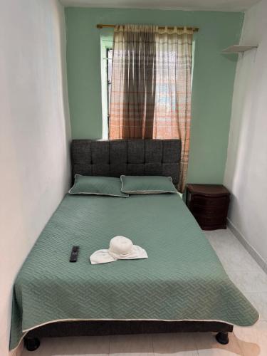 a bed with a hat sitting on top of it at Casa hotel Manhattan L&P in Choachí