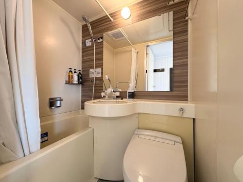a bathroom with a toilet and a sink and a mirror at APA Hotel Saitama Ageo-Ekimae in Ageo