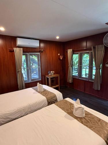a hotel room with two beds and two windows at D-Chu Mountain Haven Villas in Vang Vieng